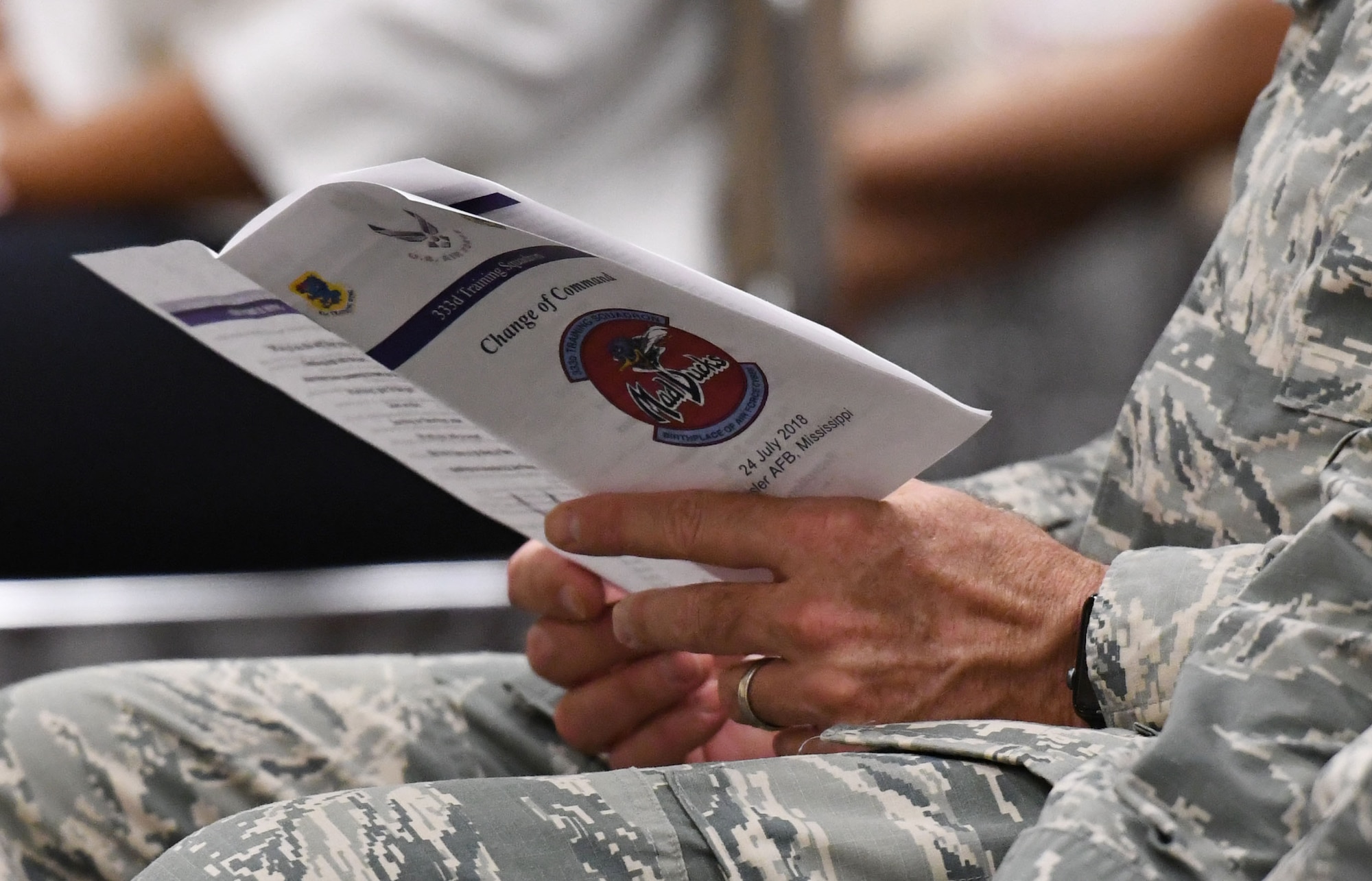 U.S. Air Force Col. Lance Burnett, 81st Training Wing vice commander, views the event program during the 333rd Training Squadron change of command ceremony in the Roberts Consolidated Aircraft Maintenance Facility at Keesler Air Force Base, Mississippi, July 24, 2018. U.S. Air Force Lt. Col. Andrew Miller, incoming 333rd TRS commander, assumed command from Lt. Col. Nathaniel Huston, outgoing 333rd TRS commander. (U.S. Air Force photo by Kemberly Groue)