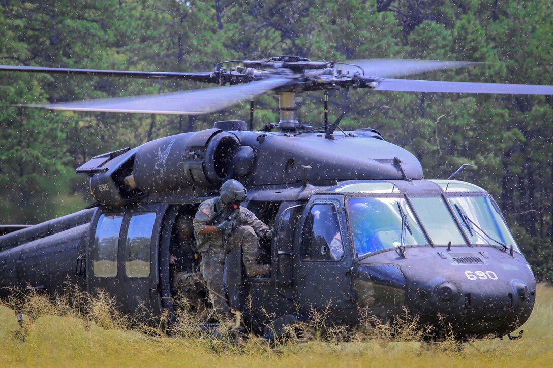 An Army crew chief disembarks from a UH-60L Black Hawk helicopter.