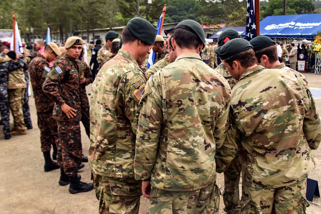 Soldiers put their hands together and wish each other good luck.