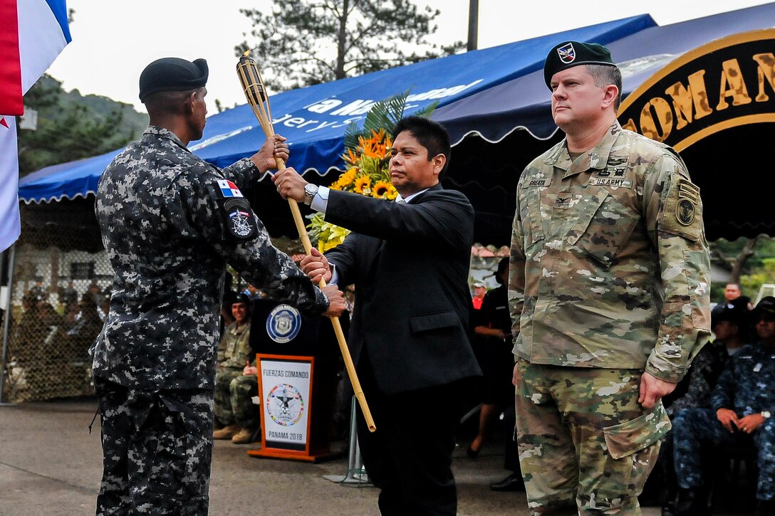 A minister of public security and U.S. soldier accept the Fuerzas Comando 2018 torch.
