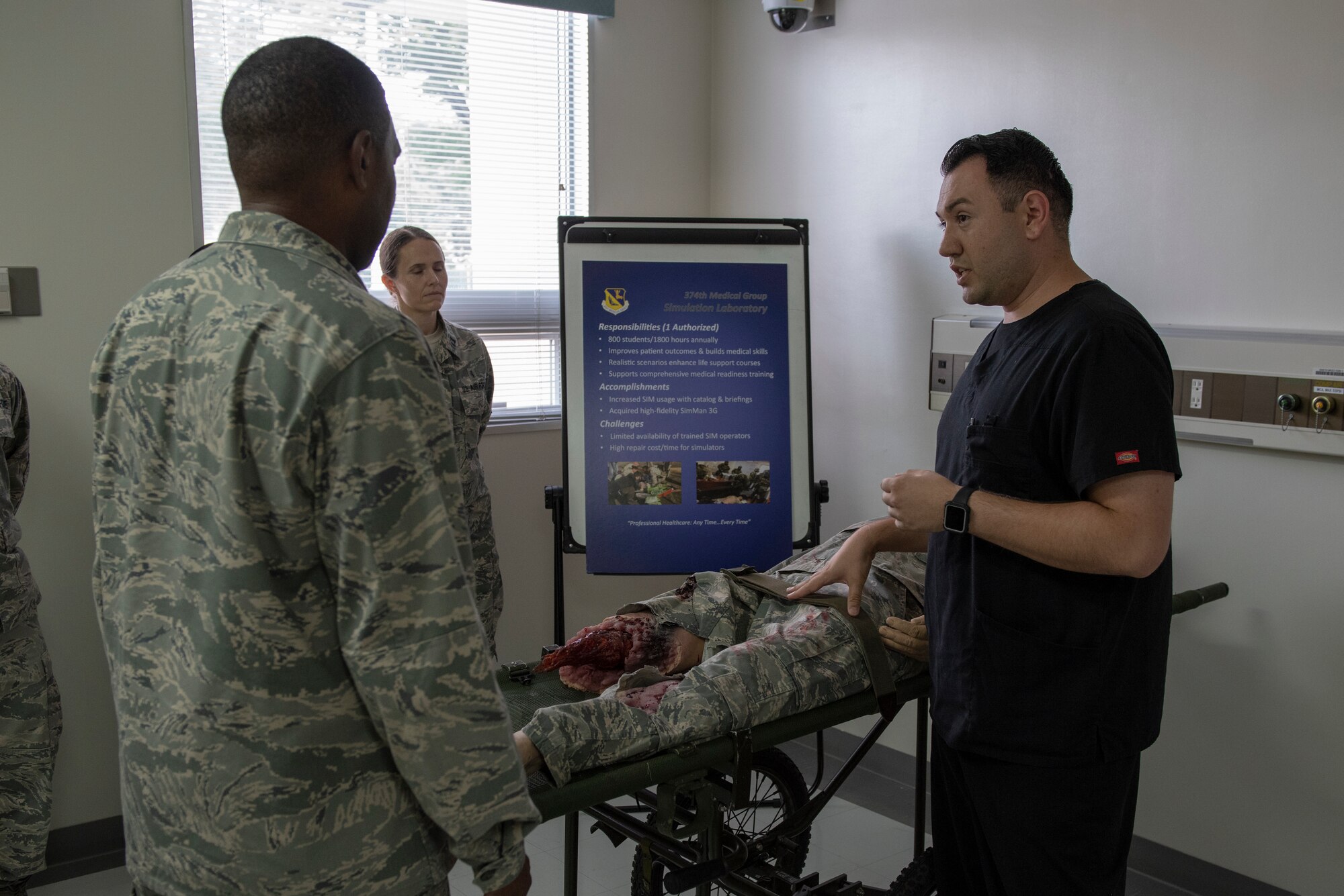 Dominic Trujillo-Hobbs, 374th Medical Group simulation operator, briefs Col. Otis C. Jones, 374th Airlift Wing commander, about the role the simulation lab has in ensuring properly trained medical personnel during the 374 MDG immersion tour at Yokota Air Base, Japan, July 24, 2018.