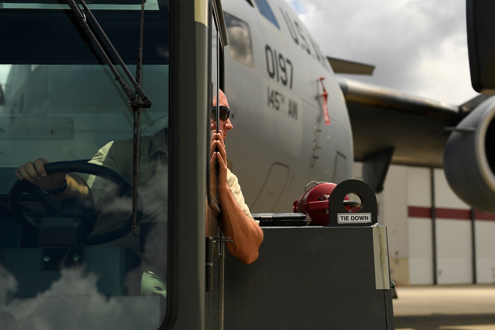U.S. Air Force Tech. Sgt. Jason Smigelski, 145th Aircraft Maintenance Squadron, looks at his spotter for hand and arm signals to direct the towing of a C-17 Globemaster III into position at the North Carolina Air National Guard Base, Charlotte Douglas International Airport, July 24, 2018. Maintenance personnel use hand and arm signals to direct each other and  park the airframe in the proper position on the flightline.
