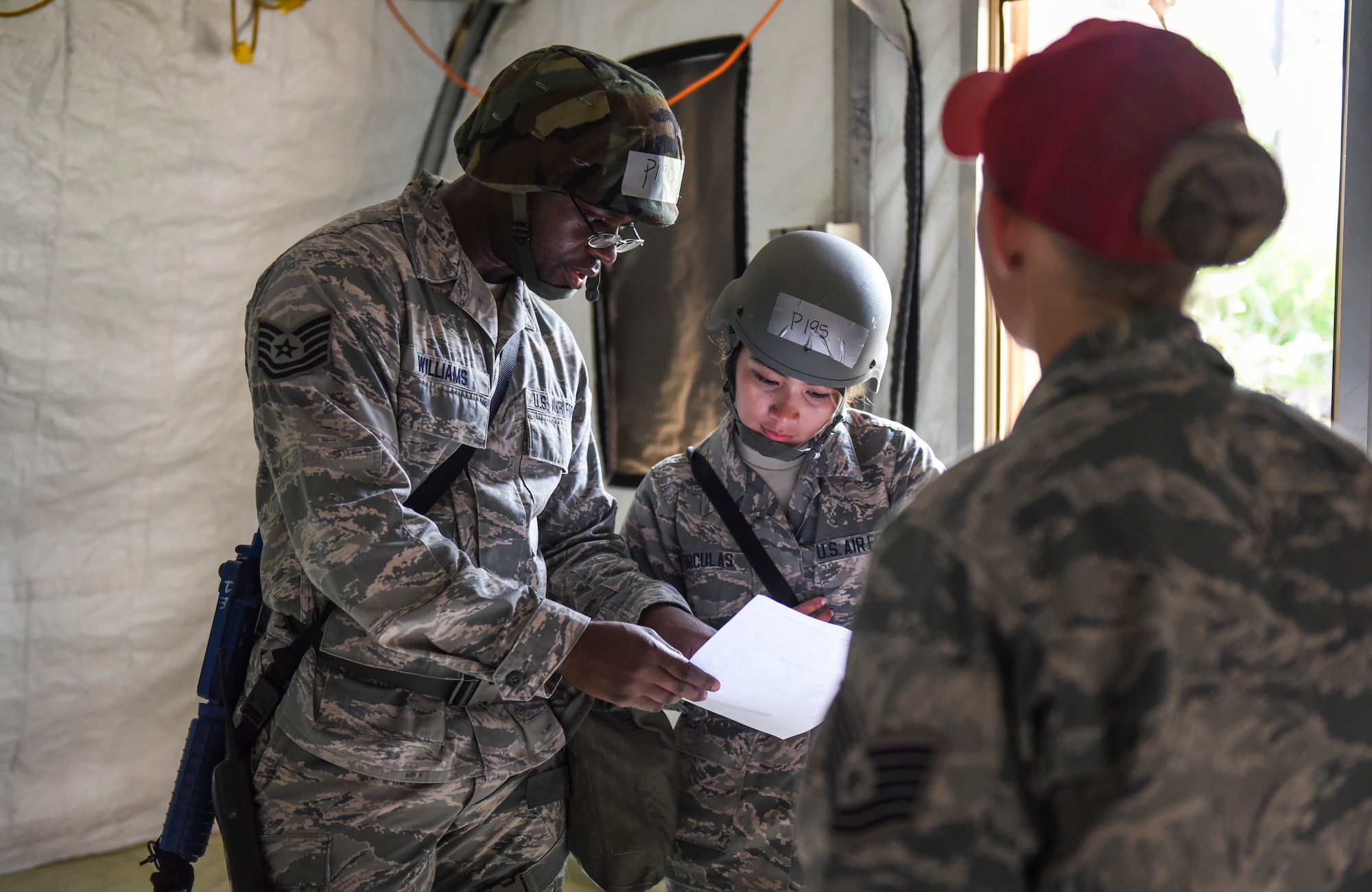 U.S. Air Force Tech. Sgt. Jean-Paul Williams, a Silver Flag training site student from the 168th Force Support Squadron, Eielson Air Force Base, Alaska, left, teaches proper paperwork review to Senior Airman Michelle Torculas, a Silver Flag training site student from the 97th Force Support Squadron, Altus Air Force Base, Oklahoma, middle, while being observed by Tech. Sgt. Kelsey Keppner, Detachment 1, 823rd Rapid Engineer Deployable Heavy Operational Repair Squadron Engineers (REDHORSE) Squadron force support squadron food operations NCO in charge, right, at Tyndall Air Force Base July 19, 2018.