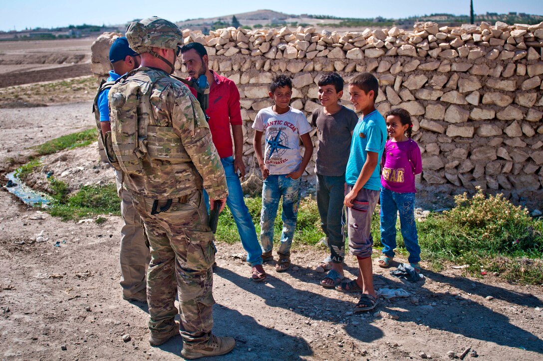 A U.S. soldier and an interpreter talk with a local villagers.