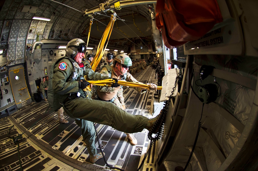 An Air Force airman pulls in the static lines after all the jumpers have exited the aircraft.