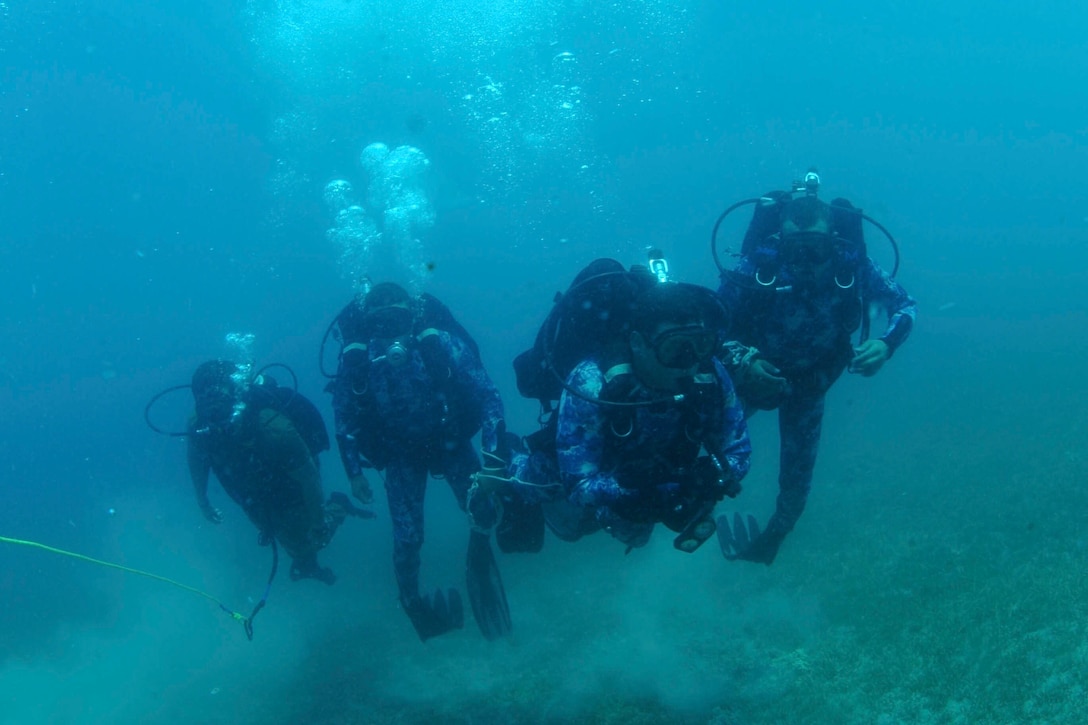 Sailors scuba dive during a military exercise.