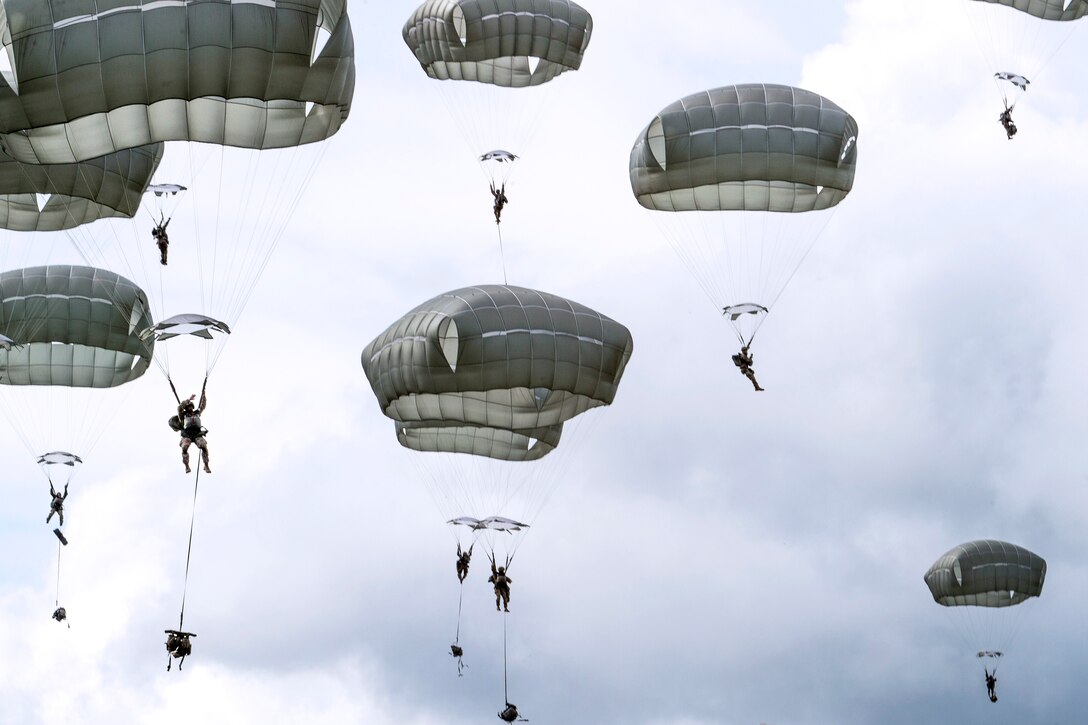 Soldiers with full chutes descend during an airborne operation.