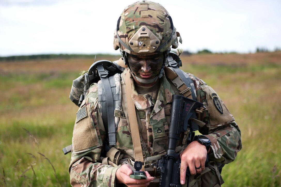 A soldier uses a lensatic compass to navigate to his follow-on objective.