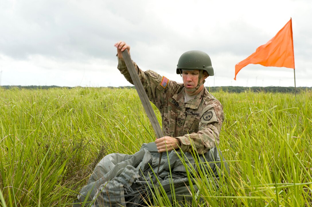 A U.S. soldier recovers his chute and gear after conducting static line airborne operation.