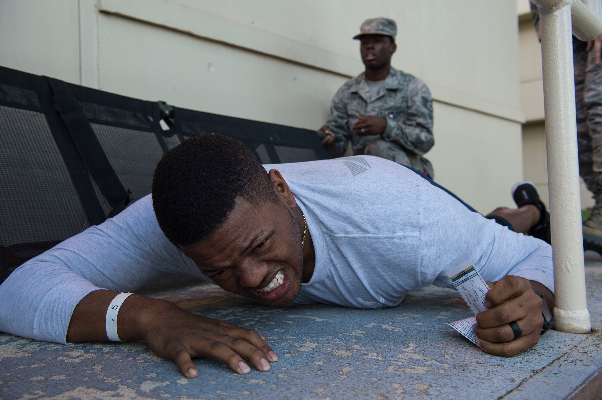 Senior Airman Damian King, 15th Medical Group, plays an injured person during a mass-casualty scenario for Rim of the Pacific (RIMPAC) at Joint Base Pearl Harbor-Hickam, July 12, 2018. Twenty-five nations, 46 ships, five submarines, about 200 aircraft and 25,000 personnel are participating in RIMPAC from June 27 to Aug. 2 in and around the Hawaiian Islands and Southern California. The world’s largest international maritime exercise, RIMPAC provides a unique training opportunity while fostering and sustaining cooperative relationships among participants critical to ensuring the safety of sea lanes and security of the world’s oceans. RIMPAC 2018 is the 26th exercise in the series that began in 1971. (U.S. Air Force photo by Tech. Sgt. Heather Redman)