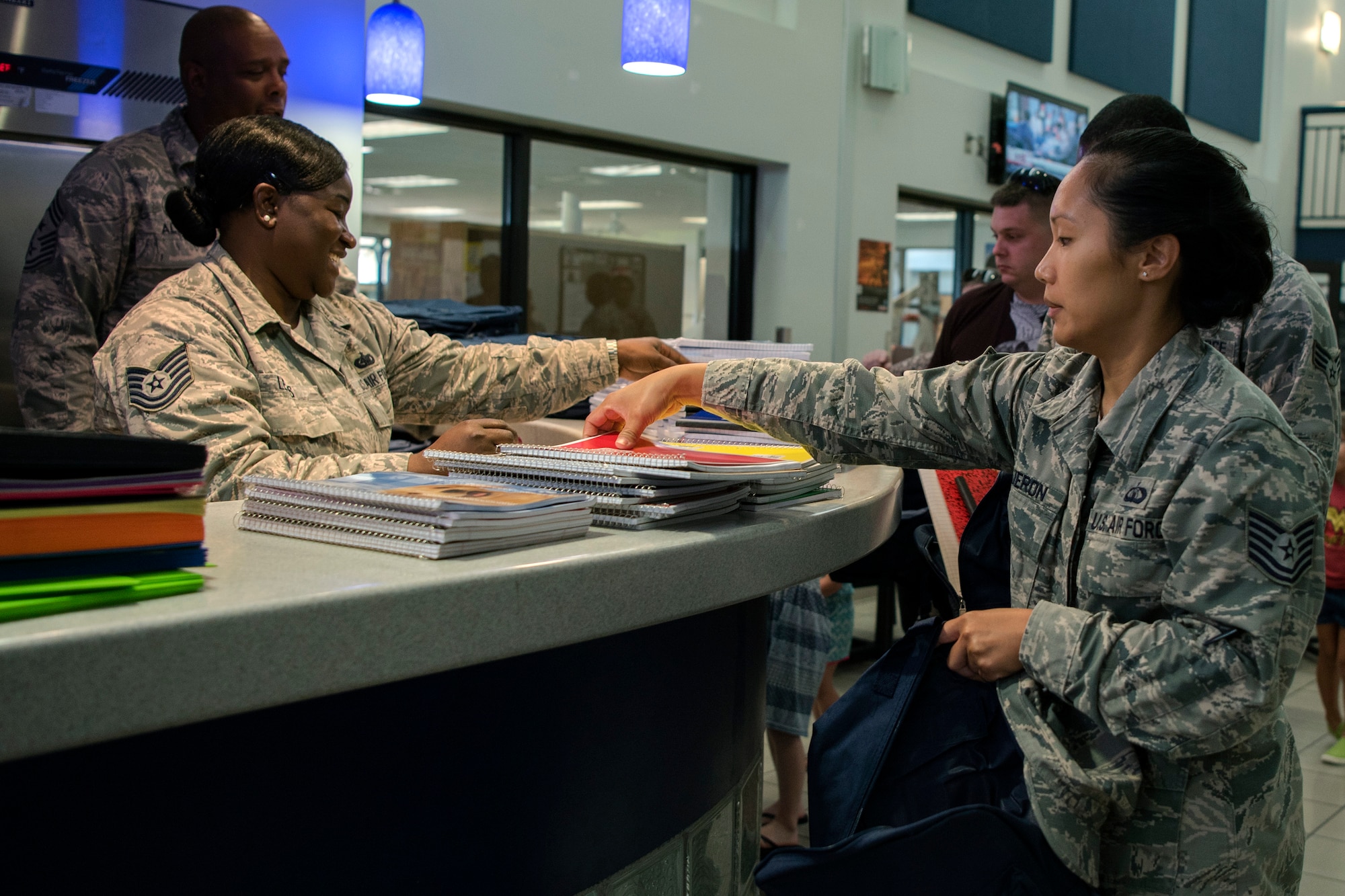 An Airman picks up a notebook at the Back-To-School Brigade, July 25, 2018, at Moody Air Force Base, Ga. With the help of Operation Homefront and the local community, the event provided Moody Airmen, grades E-1 through E-6, with school supplies. (U.S. Air Force photo by Airman Taryn Butler)