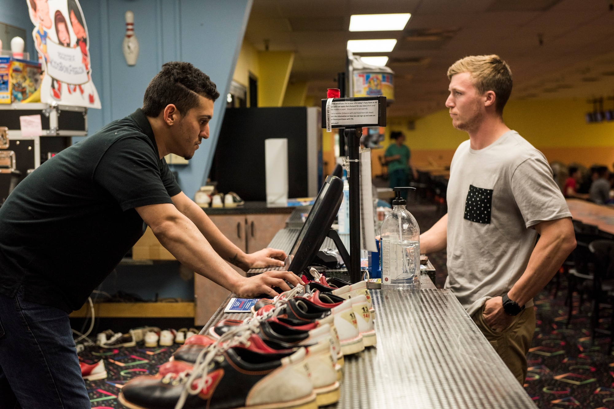 Staff Sgt. Chase McFeron, a 673d Civil Engineer Squadron explosive ordnance disposal craftsman, (right) orders a round of bowling from Luis Ruiz, Polar Bowl cashier, at Joint Base Elmendorf-Richardson, Alaska, July 13, 2018. McFeron first met Ruiz three weeks prior when Ruiz was choking at the bowling alley.