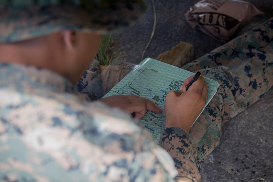 Cpl. Dennis J. Zuniga, a squad leader with Tactical Readiness Training Platoon, Marine Logistics Group Headquarters, 3rd Marine Logistics Group, writes down coordinates during land navigation at Jungle Warfare Training Center, Okinawa, Japan July 24, 2018. Land navigation is vital to an operation so that Marines can travel through terrain with ease. Zuniga is a squad leader for second squad and a basic rifleman with TRT Plt. Zunigais a native of Houston, Texas. (U.S. Marine Corps photo by Lance Cpl. Armando Elizalde)