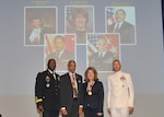 DLA Director Lt. Gen. Darrell Williams (left) and DLA Senior Enlisted Leader Navy Command Master Chief Shaun Brahmsteadt (right) stand on stage with 2018 Hall of Fame inductees Retired Army Maj. Gen. Robert Gaskill and Donna Davis following the July 26 ceremony. Photos on background screen show other Hall of Fame inductees.