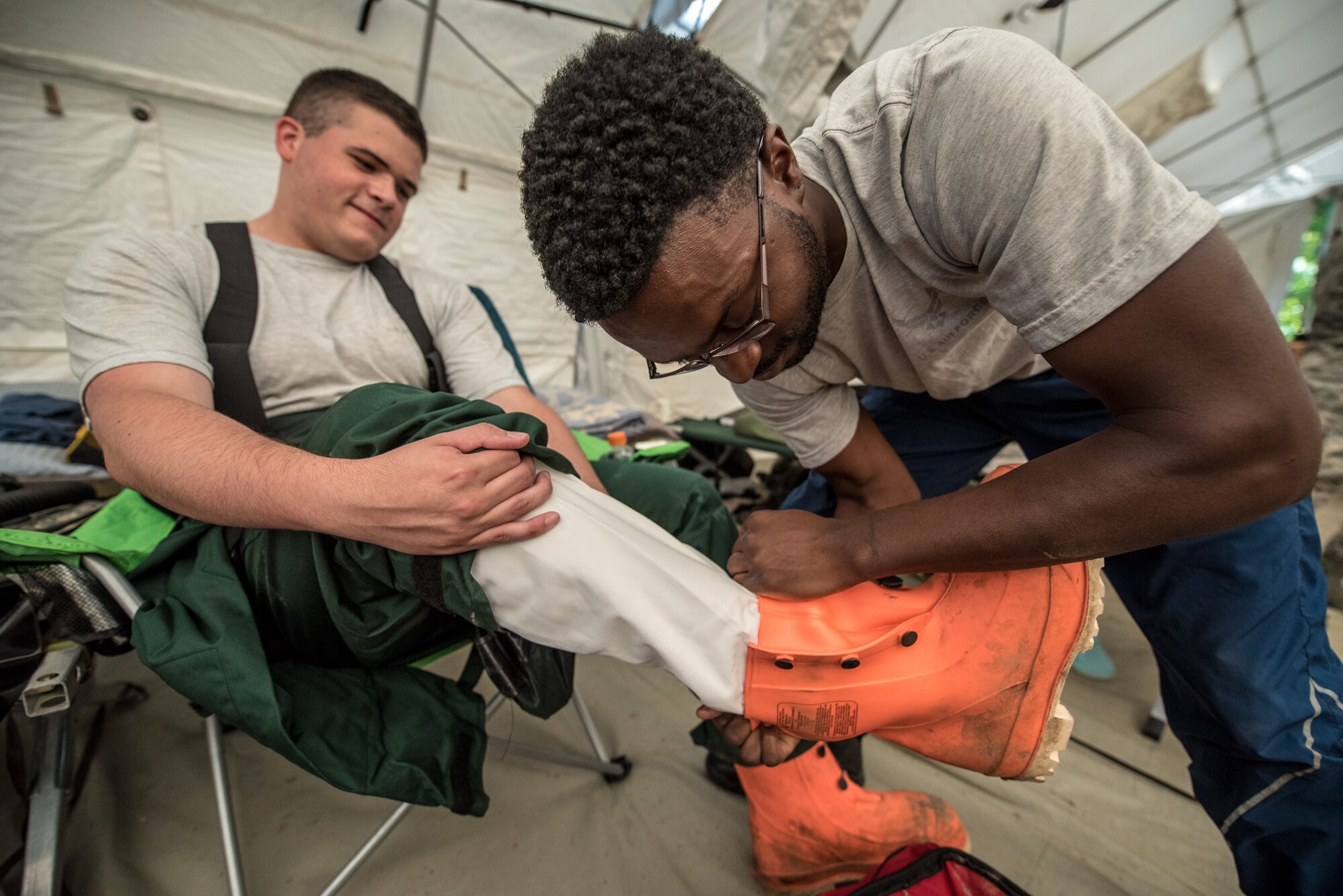 Airman First Class Anthony Cirwithian (right), a member of the Kentucky Air National Guard’s Fatality Search and Recovery Team, helps Senior Airman Ben Bohannon don boots from a MT94 chemical, biological, radiological and nuclear defense suit at Rough River State Resort Park in Falls of Rough, Ky., on July 18, 2018. Thirteen members of the 123rd Airlift Wing participated in the three-day exercise to simulate the recovery and repatriation of fallen service members. (U.S. Air National Guard photo by Master Sgt. Phil Speck)