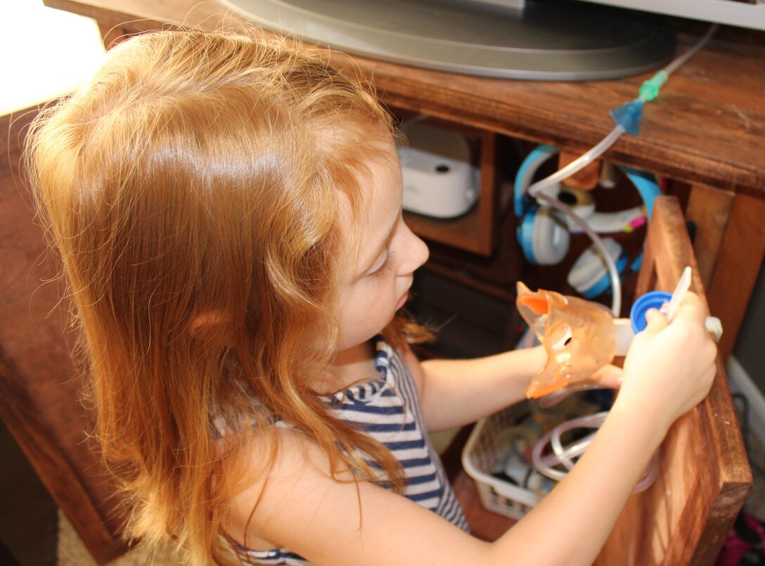 Aubrey Inman is getting her nebulizer ready for one of her daily treatments for cystic fibrosis. Cystic fibrosis is a progressive genetic disorder that causes persistent lung infections and limits the ability to breathe over time. (U.S. Air Force Photo/Stacey Geiger)