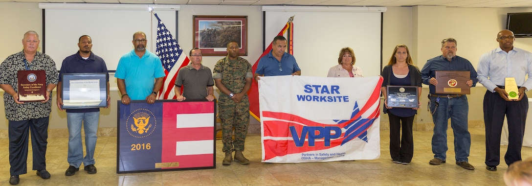 Civilian employees of Marine Corps Logistics Base Barstow present Col. Sekou Karega, MCLB Barstow base commander, with various awards the installation has earned under his command during the quarterly awards breakfast aboard MCLB Barstow, Calif., July 17.