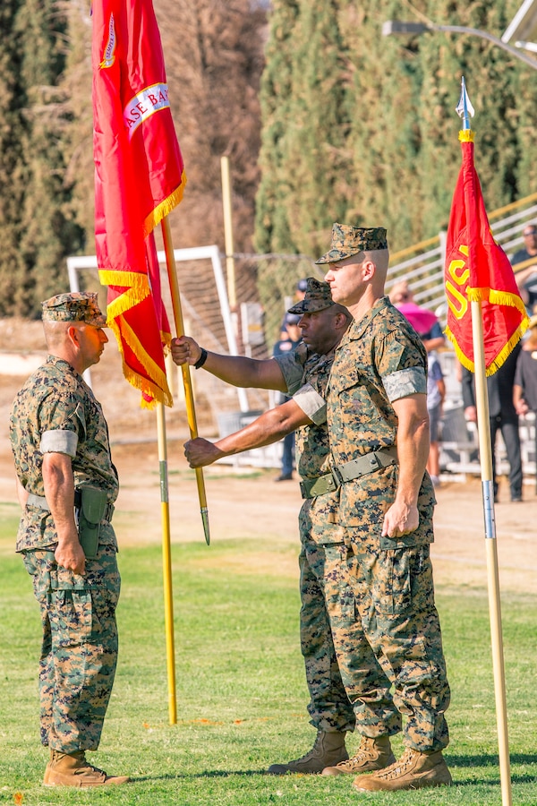 Colonel Sekou Karega, outgoing commanding officer, receives the command colors from base Sergeant Major Sergio Martinezruiz prior to relinquishing  to Col. Craig Clemans, incoming base commander, during the change of command ceremony aboard Marine Corps Logistics Base Barstow, Calif., July 19. When giving his acceptance speech, Clemans made it a point that he and all personnel are tenants of the base and to support the installation as needed.