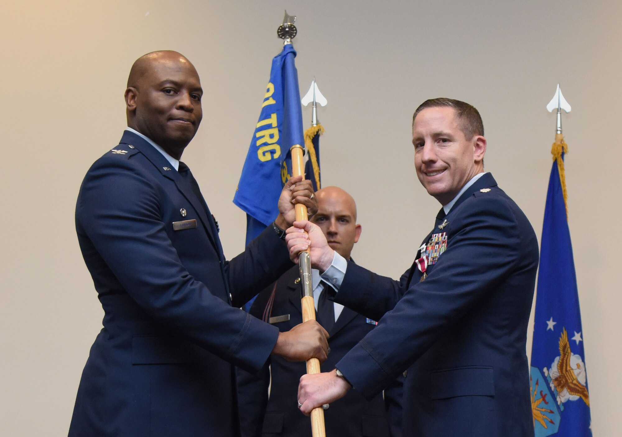 U.S. Air Force Col. Leo Lawson, Jr., 81st Training Group commander, takes the 338th Training Squadron guidon from Lt. Col. Michael Zink, outgoing 338th TRS commander, during the 338th TRS change of command ceremony in the Roberts Consolidated Aircraft Maintenance Facility at Keesler Air Force Base, Mississippi, July 26, 2018. The passing of the guidon is a ceremonial symbol of exchanging command from one commander to another. (U.S. Air Force photo by Kemberly Groue)