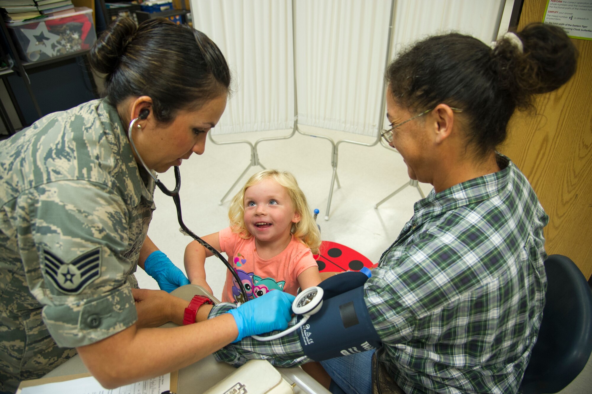 U.S. Air Force Staff Sgt. Yvette Martinez, of Goshen Ind., a medical technician with the Air Force Reserve’s 434th Aerospace Medical Squadron, Grissom Air Reserve Base, takes vital signs of a patient with the help of the patient’s granddaughter, three-year-old Willowmae, during the East Central Georgia Innovative Readiness Training in Crawfordville, Ga., July 13, 2018. An IRT provides hands-on, real-world training to improve readiness and interoperability for service members in complex contingency environments while providing key services for American communities. (U.S. Air Force photo by Master Sgt. Theanne Herrmann)