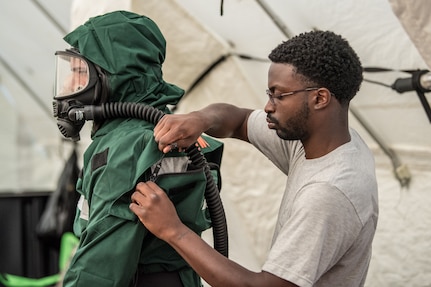 Airman First Class Anthony Cirwithian, right, a member of the Kentucky Air National Guard's Fatality Search and Recovery Team, zips up a MT94 chemical, biological, radiological and nuclear defense suit for Senior Airman Ben Bohannon, another FSRT member, at Rough River State Resort Park in Falls of Rough, Ky., on July 18, 2018. Thirteen members of the 123rd Airlift Wing participated in the three-day exercise to simulate the recovery and repatriation of fallen service members.