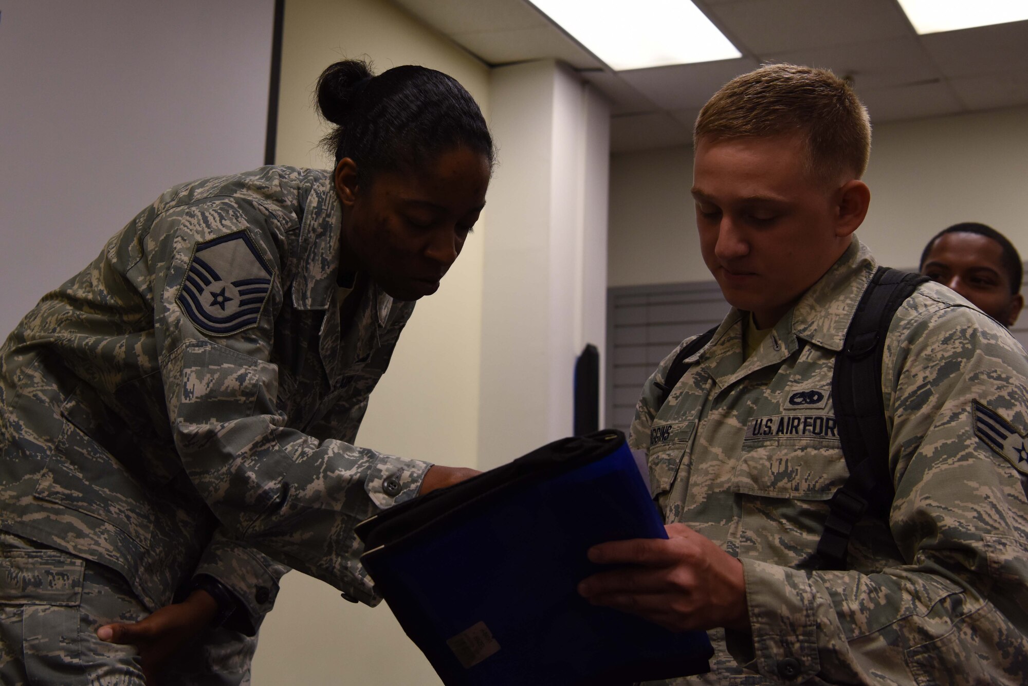 U.S. Air Force Master Sgt. Venita Miles, Pacific Air Forces in-service recruiter, looks over Palace Front paperwork for aircraft maintenance crew chief, Senior Airman Nicholas Higgins, at Kunsan Air Base, Republic of Korea, July 19, 2018. Miles services all Airmen assigned to Yokota, Misawa, Kunsan, and Osan Air Bases.
