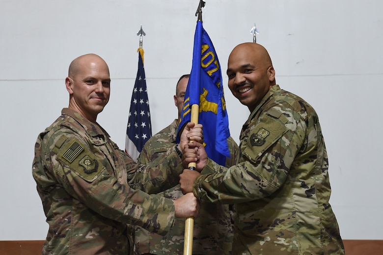 Two Airmen hold on to squadron flag