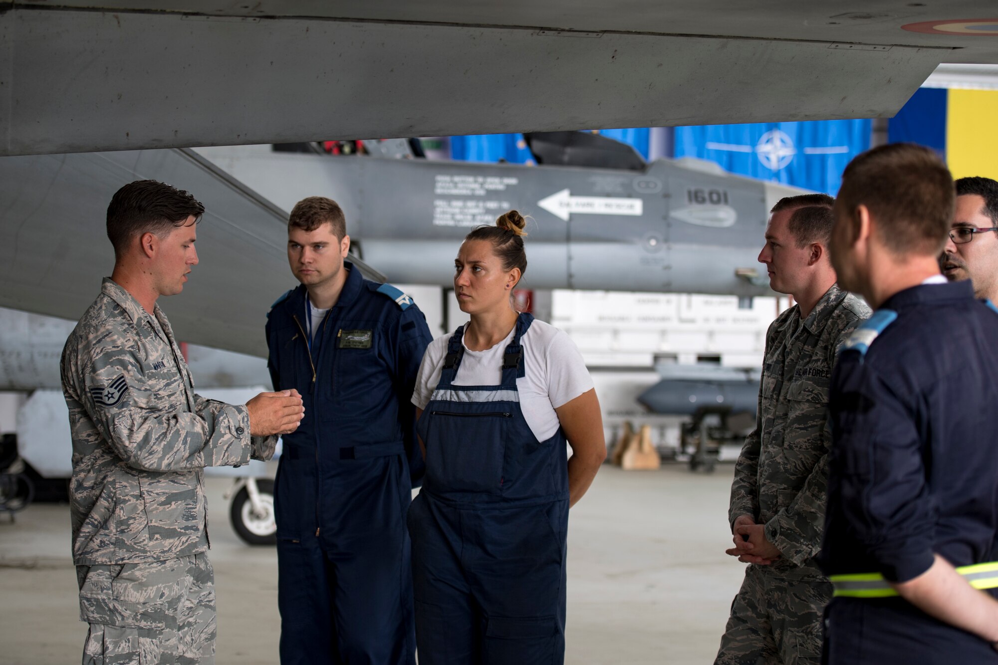 U.S. Air Force Staff Sgt. Johnathan Martin, 31st Maintenance Squadron electrical and environmental craftsman, discusses aircraft maintenance with Romanian air force personnel at Borcea Air Base, Romania, July 25, 2018. Martin traveled from Aviano Air Base, Italy, to support the 435th Contingency Response Support Squadron from Ramstein Air Base, Germany, with providing training to the Romanian air force. (U.S. Air Force photo by Senior Airman Devin Boyer)