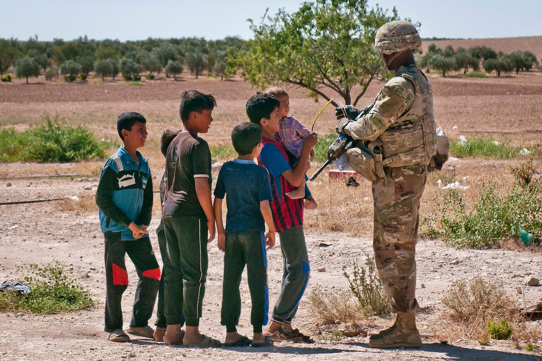 A soldier hands out candy to a group of children.