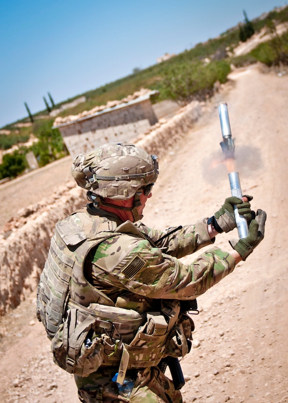 A U.S. soldier fires a star cluster pyrotechnic into the sky.