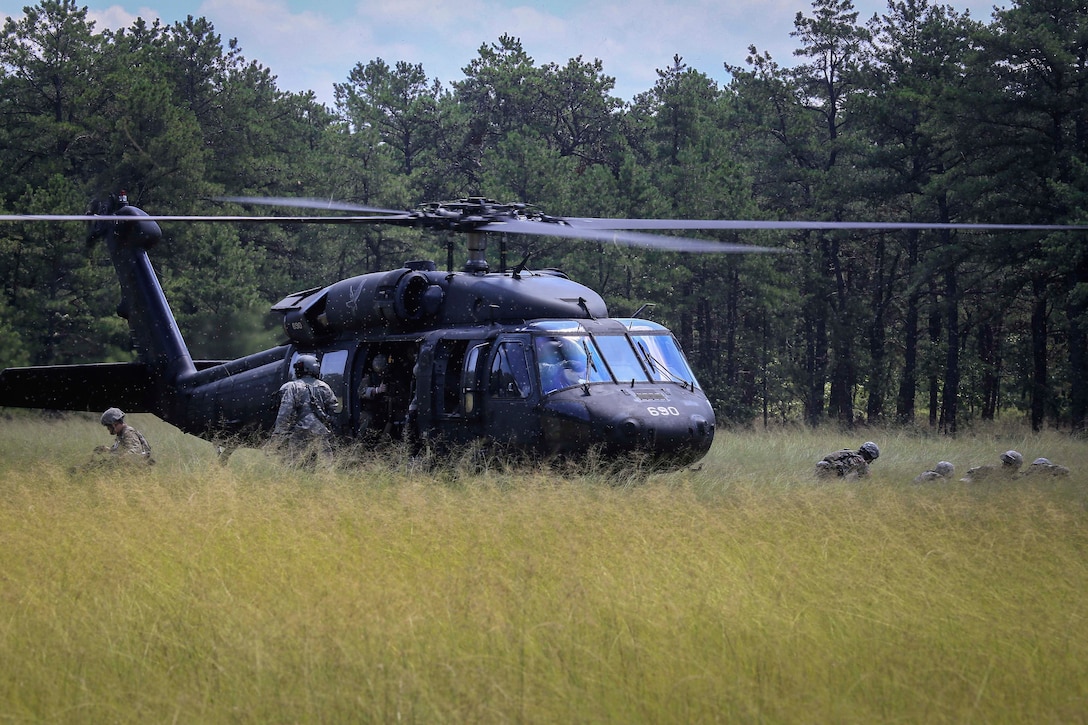 Soldiers disembark from a UH-60L Black Hawk helicopter.
