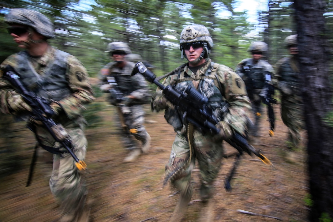 Soldiers maneuver through the woods toward their follow-on objective.