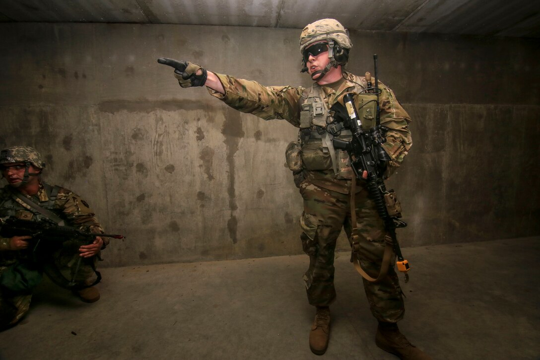 A soldier indicates where his team members are to evacuate an enemy combatant during training.