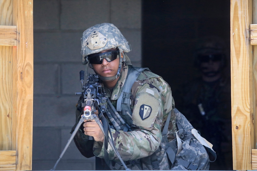 A soldier provides cover while team members secure a building.