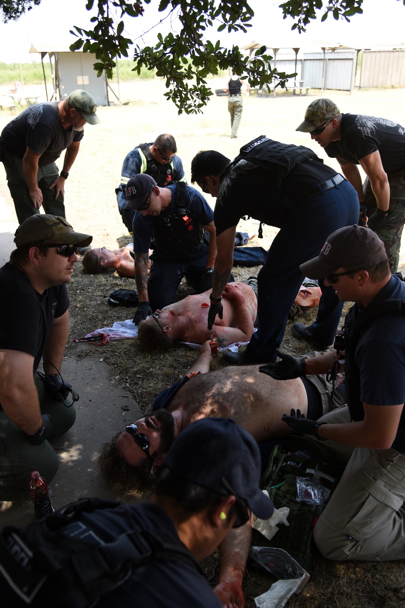 Firefighters assess simulated injuries during a Tactical Combat Casualty Care Course near building 3070 on Goodfellow Air Force Base, Texas, July 27, 2018. The course included an active shooter exercise to stress test the students. (U.S. Air Force photo by Staff Sgt. Joshua Edwards/Released)