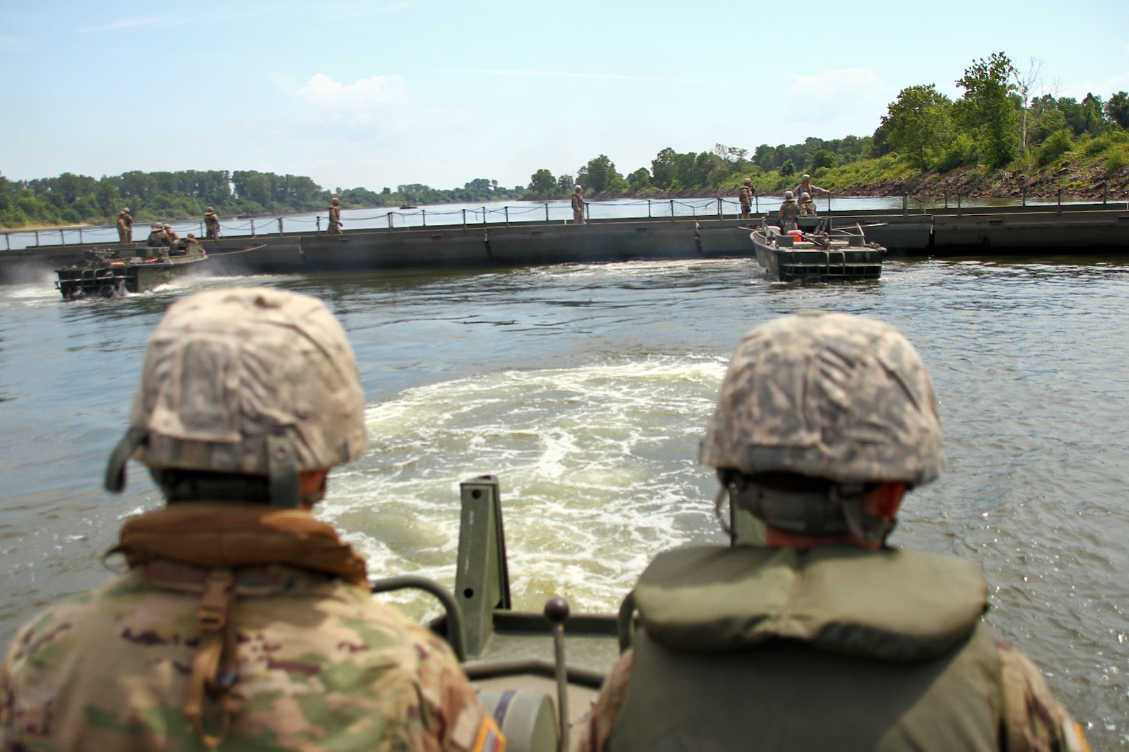Soldiers with the 2061st Multi-Role Bridge Company steer their boat away from bridge construction during River Assault 2018 on the Arkansas River near Fort Smith, Ark., July 25, 2018. The Kentucky Guard members participated with Army Reserve, active duty Army and Marine Corps units for the annual engineer exercise.