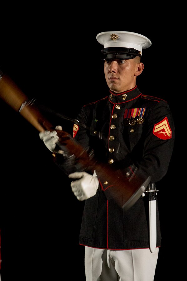 Corporal Darius Mick, rifle inspection team, U.S. Marine Corps Silent Drill Platoon, executes precision rifle drill movements during the Staff-Noncommissioned Officer Friday Evening Parade at Marine Barracks Washington D.C., July 27, 2018. During the SNCO Friday Evening Parade, SNCO’s assume the billets of key leaders’ marching positions normally filled by officers and non-commissioned officers.