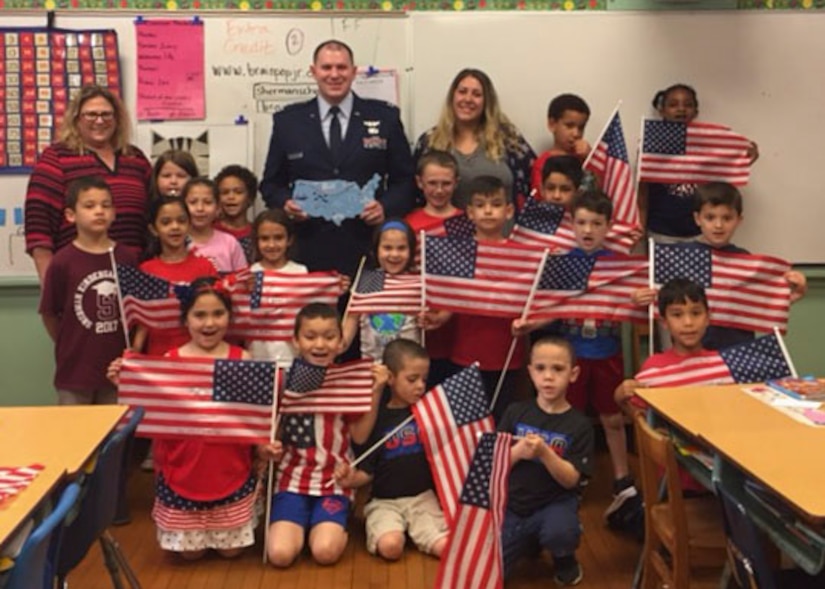U.S. Air Force Capt. John DeLaurentis, 363rd Intelligence, Surveillance and Reconnaissance Wing deputy director, plans and programs, poses for a photo with students and teachers at Sherman Elementary School in Roselle, New Jersey, May 30, 2018. DeLaurentis visited the first-graders to show appreciation for a surprise package he received from the class. (Courtesy Photo)