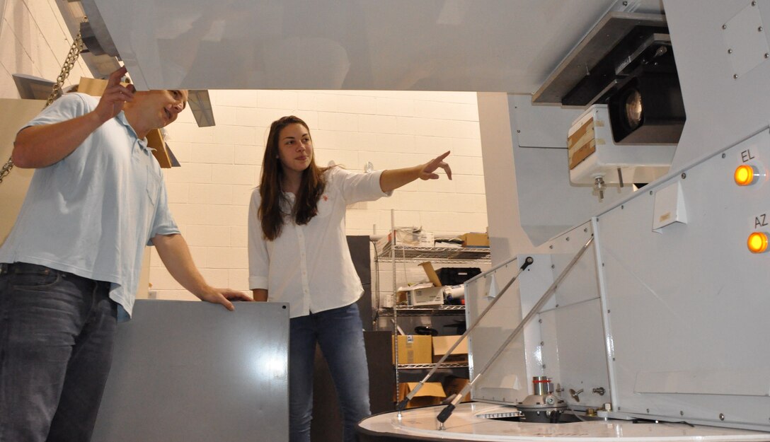 IMAGE: DAHLGREN, Va. (July 10, 2018) - Sarah Wessel and her mentor, Naval Surface Warfare Center Dahlgren Division engineer Matt Henning, examine the Advanced Beam Control Locating and Engaging - Enhanced Tracking System (ABLE-ETS) gimbal. The ABLE ETS Gimbal is part of a pointing and image tracking system. Last summer, Wessel converted the gimbal's pointing controller Simulink code into C++ code. ABLE-ETS is a Joint Technology Office funded test bed for maturing directed energy and high-energy laser technologies, including tracking, sensors, and lasers. 

Wessel is interning at Dahlgren through the STEM (science, technology, engineering and mathematics) Student Employment Program (SSEP). The program provides direct hire authority for undergraduate and graduate degree seeking students enrolled in STEM majors. The program was established to provide interns with exposure to public service, enhance educational experience, and possibly provide financial aid to support educational goals. Additionally, this program will provide a streamlined and accelerated hiring process to compete successfully with private industry for high-quality scientific, technical, engineering, or mathematics students for filling scientific and engineering positions.