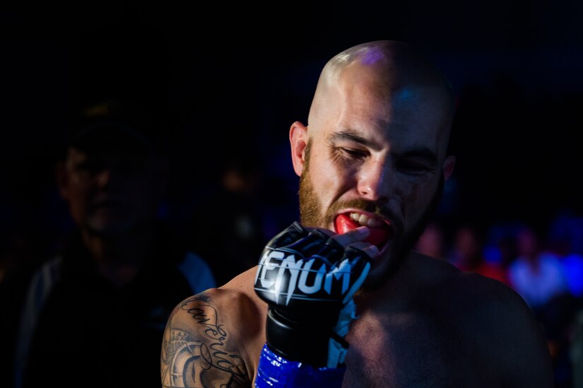 Chris Rollins, featherweight fighter, puts in his mouth guard before a live broadcast Legacy Fighting Alliance mixed martial arts fight as part of Fort Eustis' centennial celebration at Joint Base Langley-Eustis, Virginia, July 27, 2018.