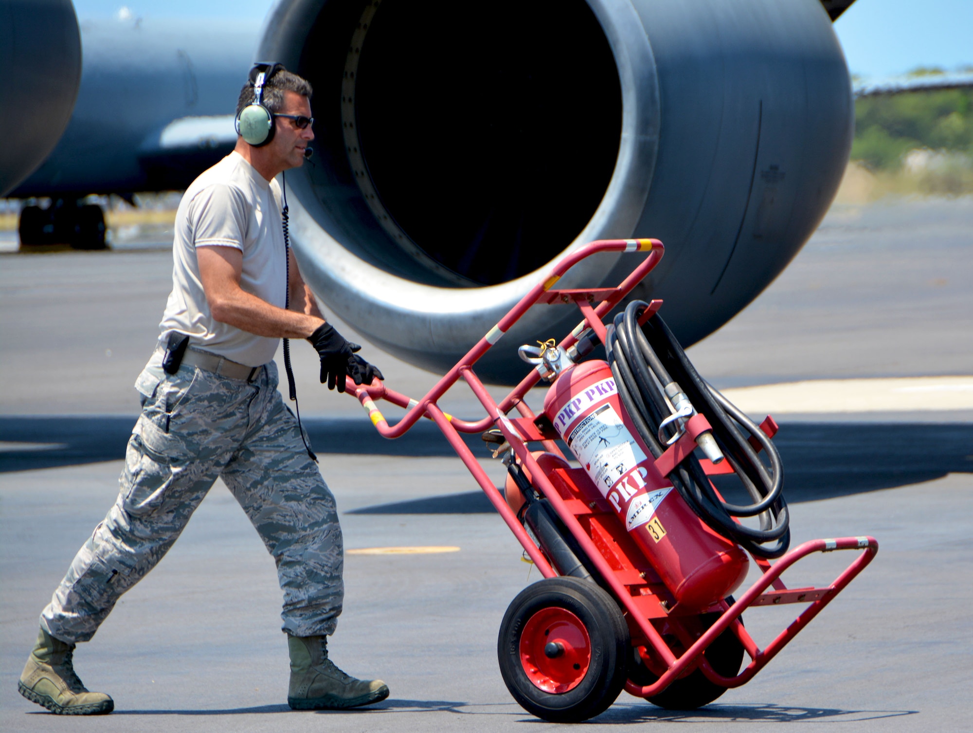 Tech. Sgt. Timothy Hardy, 507th Aircraft Maintenance Squadron crew chief from Tinker Air Force Base, Oklahoma, rolls a fire extinguisher into place near a 97th Air Mobility Wing KC-135 Stratotanker from Altus Air Force Base, Oklahoma, during the Rim of the Pacific (RIMPAC) exercise July 16. Twenty-five nations, 46 ships, five submarines, and about 200 aircraft and 25,000 personnel are participating in RIMPAC from June 27 to Aug. 2 in and around the Hawaiian Islands and Southern California. The world’s largest international maritime exercise, RIMPAC provides a unique training opportunity while fostering and sustaining cooperative relationships among participants critical to ensuring the safety of sea lanes and security of the world’s oceans. RIMPAC 2018 is the 26th exercise in the series that began in 1971. (U.S. Air Force photo by Tech. Sgt. Samantha Mathison)