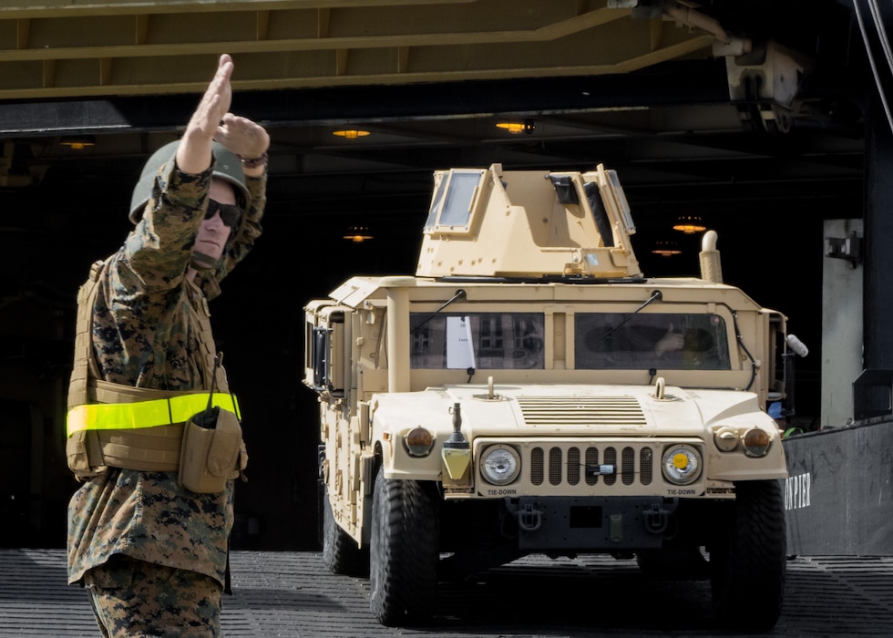 Cpl. Bradley Graczyk, combat engineer with Combat Logistics Regiment 45 directs a Humvee offloading from USNS Sgt. William R. Button during a maritime prepositioning force offload at the port of Klaipeda, Lithuania, May 23, 2018.