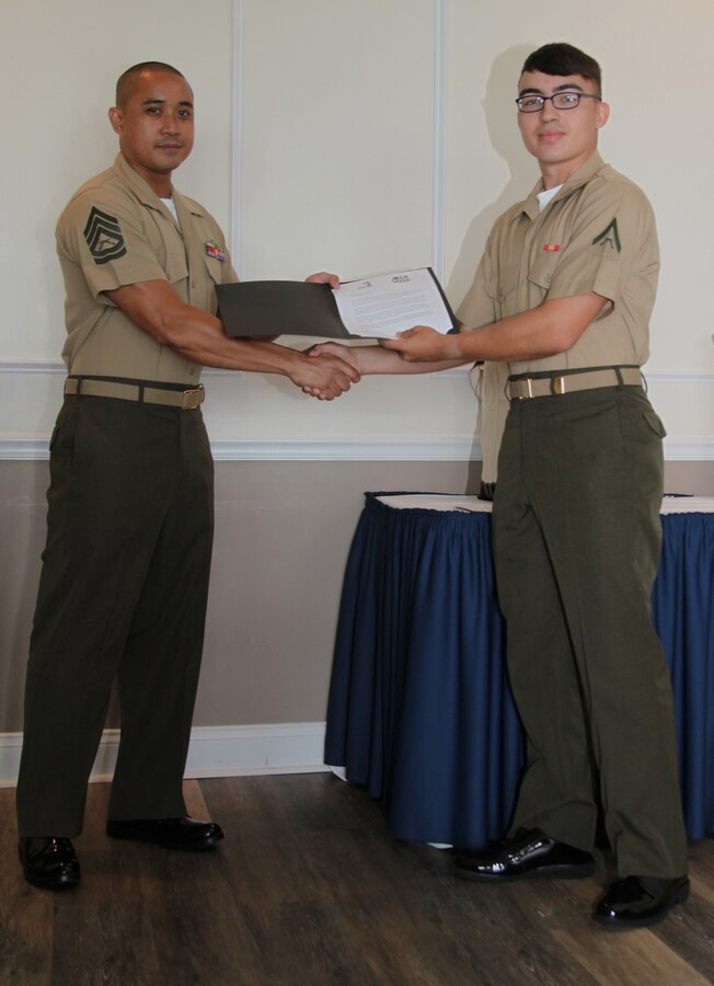 Gunnery Sgt. T. J. Tabora, left, presents Lance Cpl. Zale Harris with a recognition certificate during a Service Person of the Quarter luncheon hosted by the Carteret County Chamber of Commerce’s Military Affairs Committee at Pine Knoll Shores, N.C., July 20, 2018. The committee honors service members for their continual dedication to the local community through volunteering. Harris volunteered more than 130 hours, improving the quality of life in the local communities surrounding Marine Corps Air Station Cherry Point, N.C. Tabora is an instructor at the Center for Naval Aviation Technical Training at Marine Corps Air Station Cherry Point and Harris is a student at CNATT. (U.S. Marine Corps photo by Lance Cpl. Alexandra Santos Arambulo)