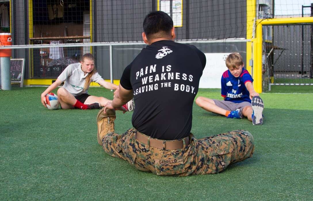 Sgt. Louigene Gabrillo, a recruiter at Recruiting Substation San Mateo, California, conducts a wake up and workout exercise with 14-year-old Skylar Jordan and 11-year-old Zach Cuddy, both from Whitman, Massachusetts, before the second day of the Rugby World Cup Sevens in San Francisco, California, July 21, 2018. This year, the Marine Corps attended the Rugby World Cup Sevens as part of its partnership with USA Rugby. Rugby players tend to share the fighting spirit embodied in Marines and by partnering with USA Rugby, the national governing body for the sport in America, the Marine Corps will reach a broad cross-section of high school and collegiate-aged rugby players as well as an ever-growing influencer network of coaches, referees, rugby alumni and parents.