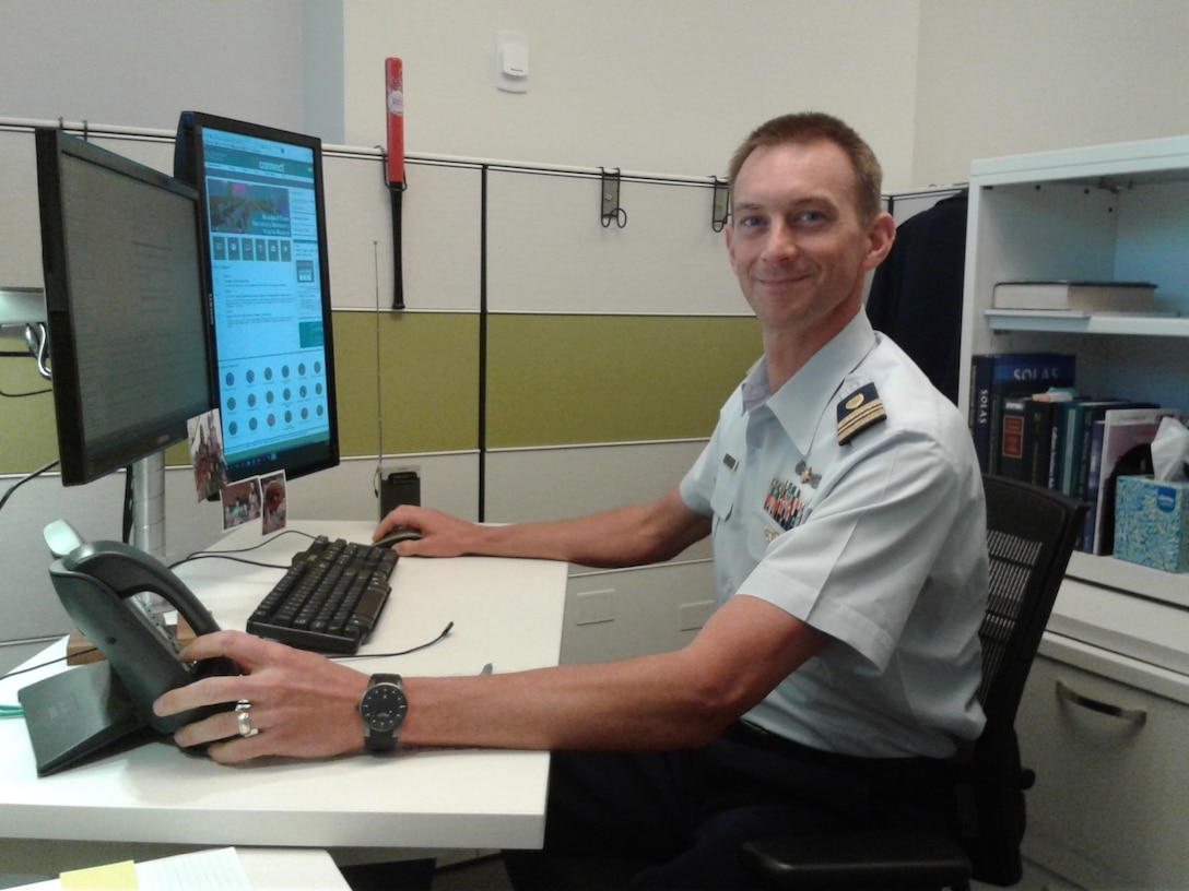 A Coast Guard officer sits at a computer terminal.