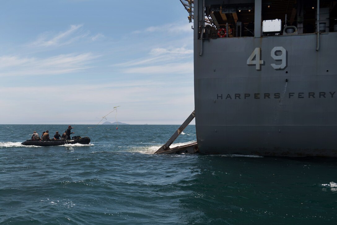 A U.S. sailor throws a retrieving rope from a combat rubber raiding craft.