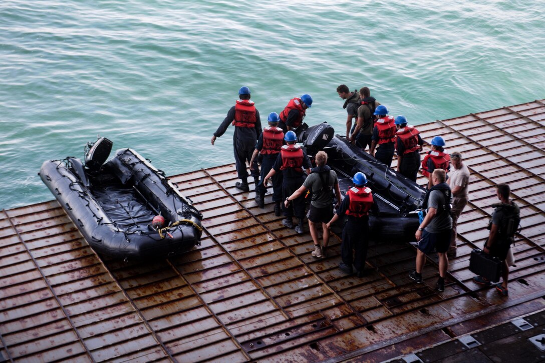 Sailors move a combat rubber raiding craft to the ship’s stern gate.