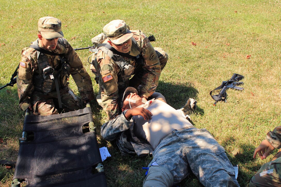 Soldiers prepare to move a mock casualty onto a stretcher during combat lifesaving training.