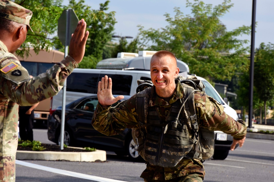 A soldier receives a high-five while completing the ruck march event.