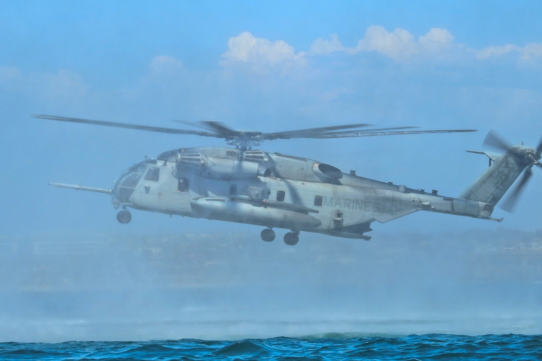 U.S. Marines and Australian sailors prepare to jump from a CH-53E Super Stallion helicopter.